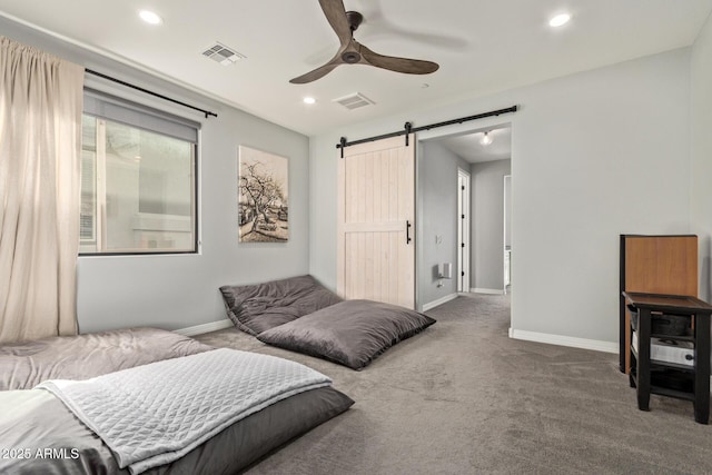 bedroom with carpet, visible vents, baseboards, and a barn door