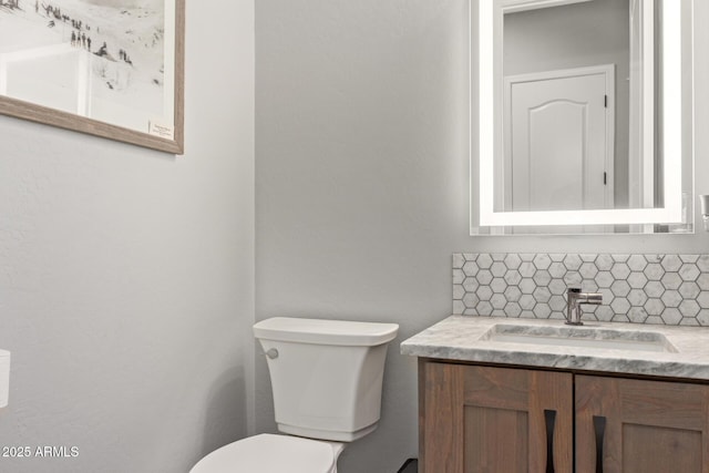 half bath featuring toilet, vanity, and decorative backsplash