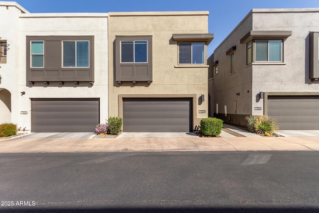 townhome / multi-family property with an attached garage, concrete driveway, and stucco siding