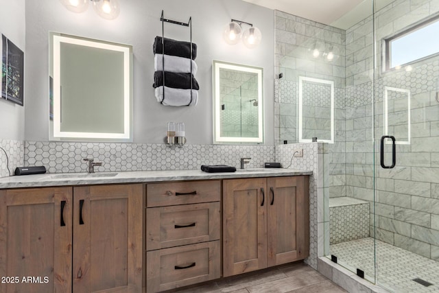 full bathroom with double vanity, tasteful backsplash, wood finished floors, a shower stall, and a sink