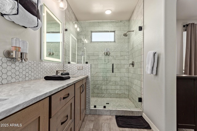 bathroom with a shower stall, wood finished floors, backsplash, and vanity