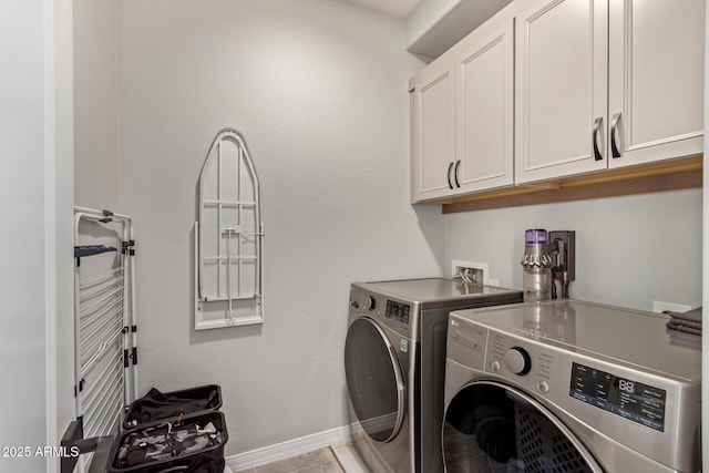 washroom with cabinet space, baseboards, and washing machine and clothes dryer