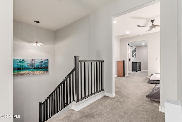 hall featuring carpet floors, baseboards, visible vents, and an upstairs landing