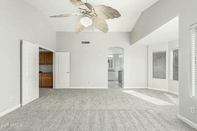 interior space featuring light carpet, high vaulted ceiling, ceiling fan, and ensuite bathroom