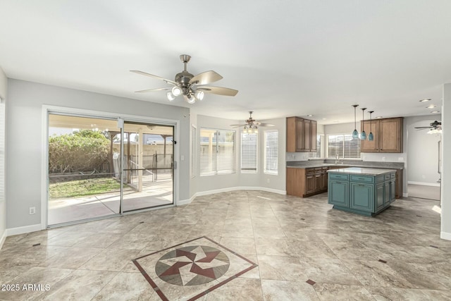 kitchen with ceiling fan, decorative light fixtures, sink, and a kitchen island