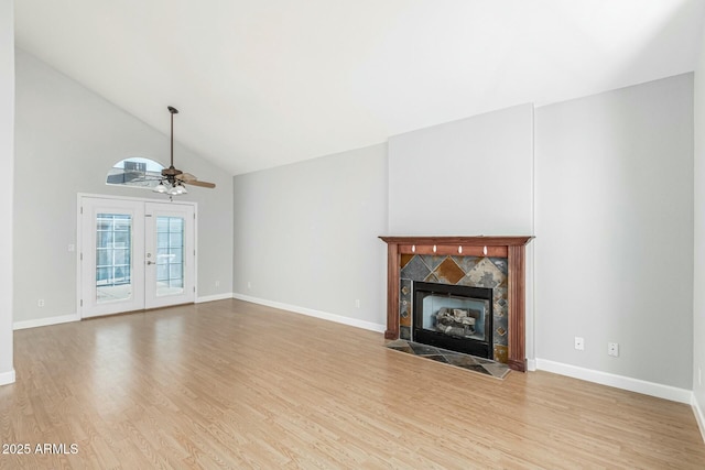 unfurnished living room with a fireplace, french doors, ceiling fan, and light wood-type flooring