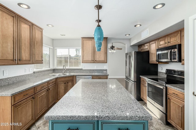 kitchen featuring sink, decorative light fixtures, a kitchen island, and appliances with stainless steel finishes