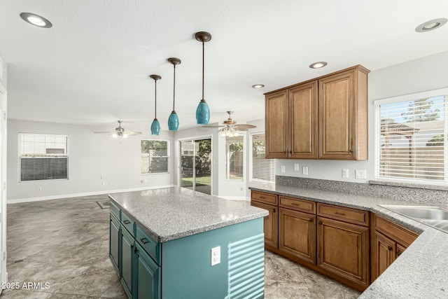 kitchen featuring pendant lighting, ceiling fan, a center island, and a healthy amount of sunlight