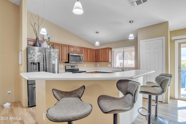 kitchen with stainless steel appliances, light countertops, hanging light fixtures, visible vents, and a sink