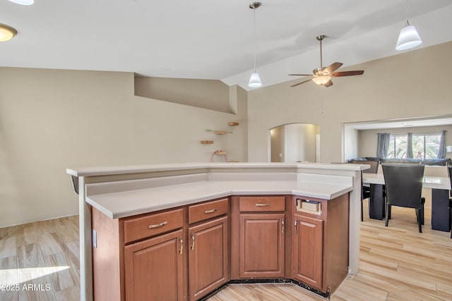 kitchen featuring light wood-type flooring, arched walkways, pendant lighting, and lofted ceiling