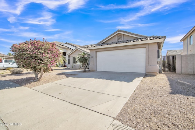 view of front facade with an attached garage, fence, a tile roof, concrete driveway, and stucco siding