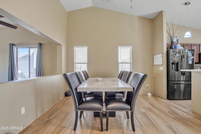 dining space featuring light wood-type flooring, plenty of natural light, and high vaulted ceiling