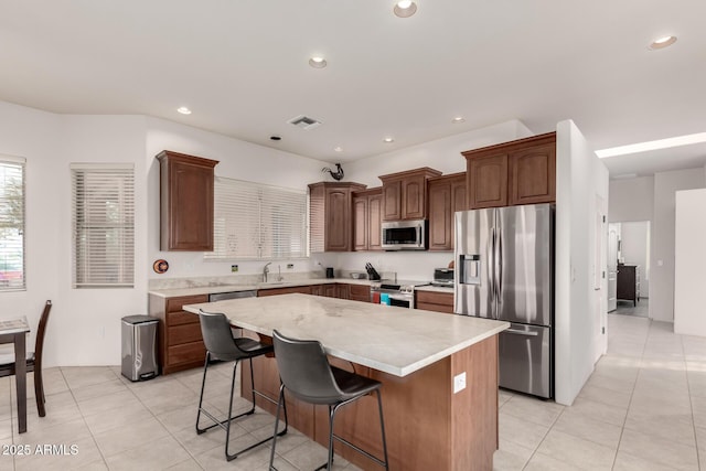 kitchen featuring a kitchen bar, light tile patterned floors, appliances with stainless steel finishes, and a center island