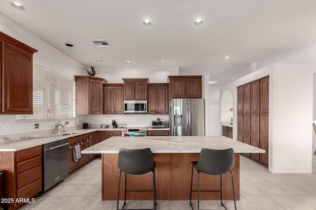 kitchen featuring a kitchen bar, sink, stainless steel appliances, and a kitchen island