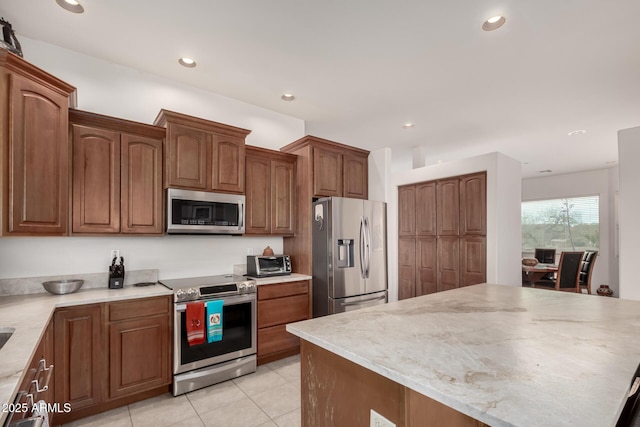 kitchen featuring light tile patterned floors, appliances with stainless steel finishes, light stone counters, and a kitchen island