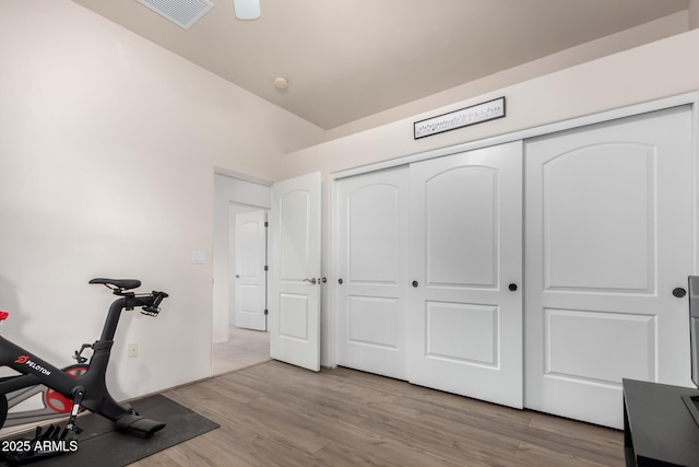 workout room featuring light hardwood / wood-style flooring and lofted ceiling