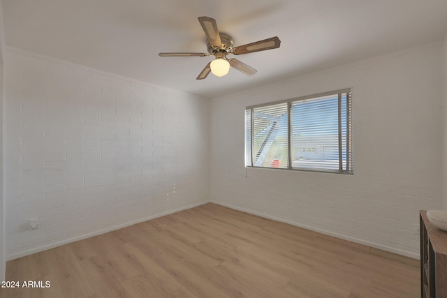 unfurnished room with ceiling fan, light wood-type flooring, and brick wall