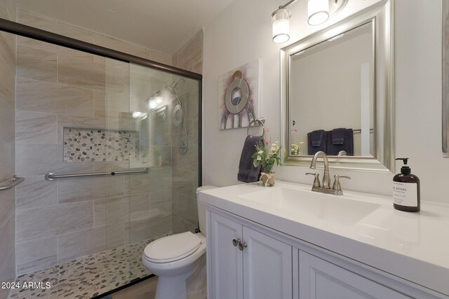 bathroom featuring vanity, toilet, and a shower with shower door