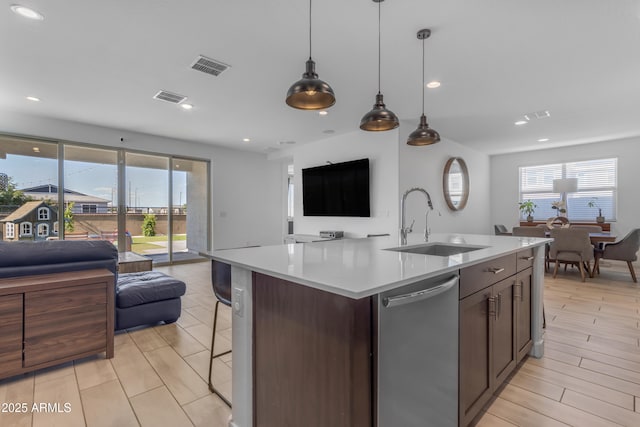 kitchen featuring open floor plan, dishwasher, a sink, plenty of natural light, and recessed lighting