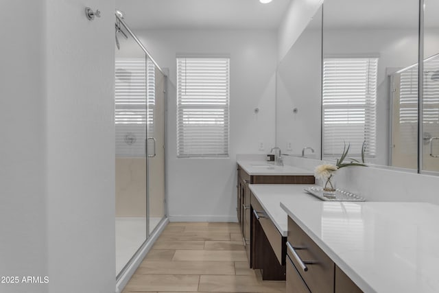 bathroom featuring vanity, a shower stall, baseboards, and wood finished floors