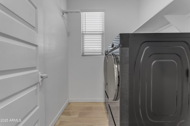 laundry room featuring washing machine and dryer, light wood-type flooring, and baseboards