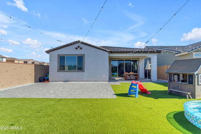 rear view of house featuring a patio area, a tiled roof, stucco siding, and an outbuilding