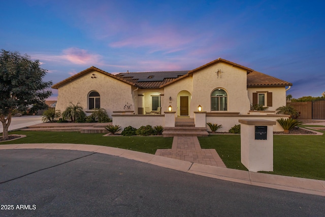 mediterranean / spanish home with solar panels and a yard