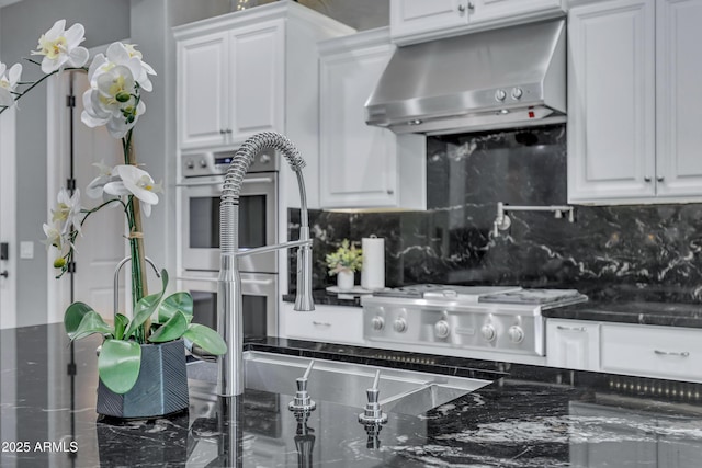 kitchen featuring ventilation hood, decorative backsplash, white gas stovetop, and white cabinetry