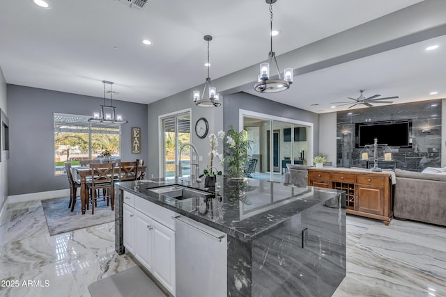 kitchen featuring sink, ceiling fan, dark stone countertops, an island with sink, and white cabinetry