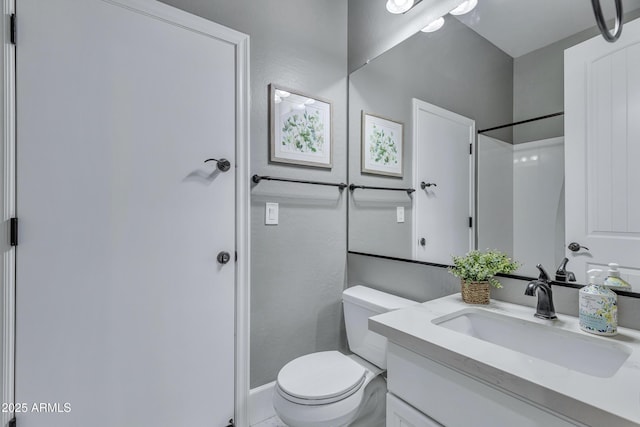 bathroom with vanity, toilet, and a shower