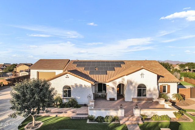 mediterranean / spanish house featuring solar panels, a patio, and a front lawn