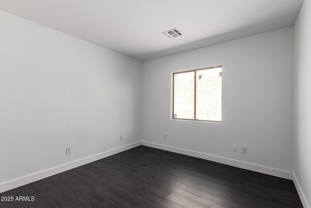 empty room with dark wood-style flooring, baseboards, and visible vents