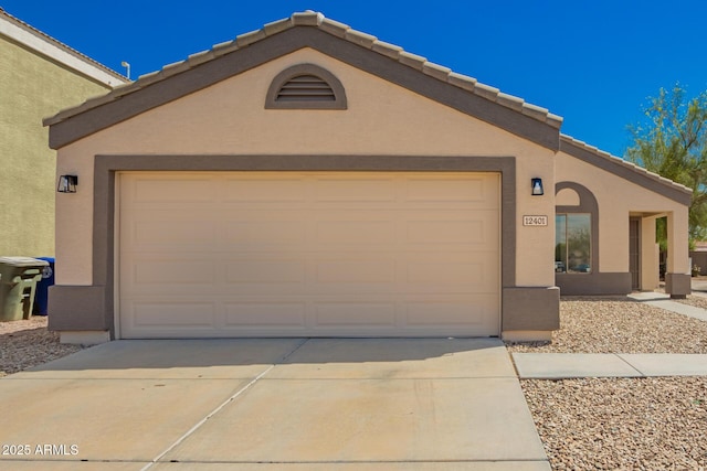 view of front facade featuring stucco siding, a tile roof, a garage, and concrete driveway