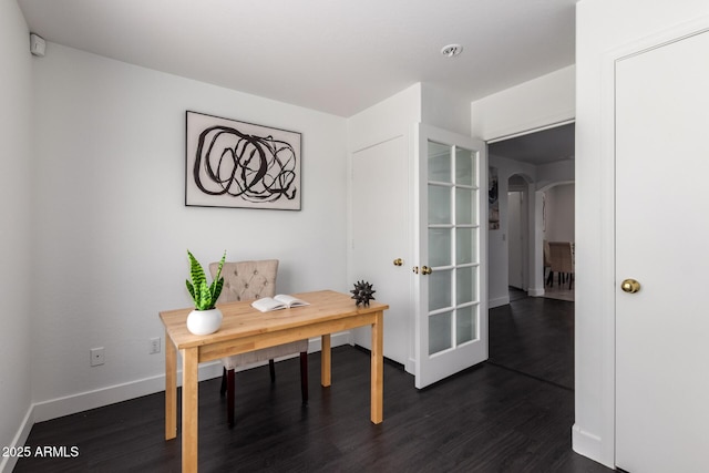 office area with arched walkways, dark wood-style flooring, and baseboards
