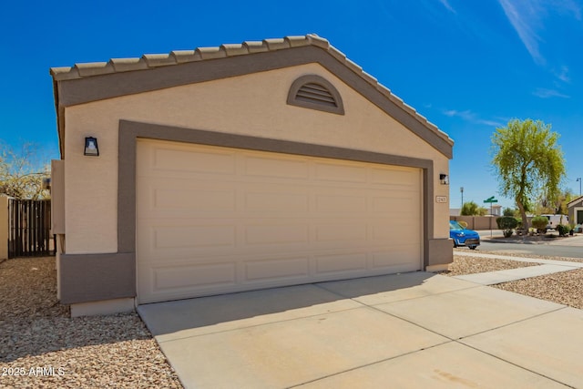 garage with concrete driveway and fence