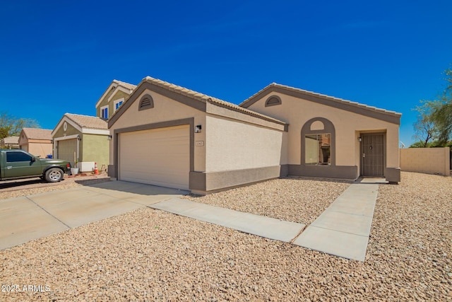 view of front of house with stucco siding, fence, a tiled roof, driveway, and a garage