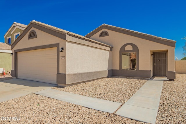 view of front of home featuring stucco siding, a garage, a tiled roof, and concrete driveway