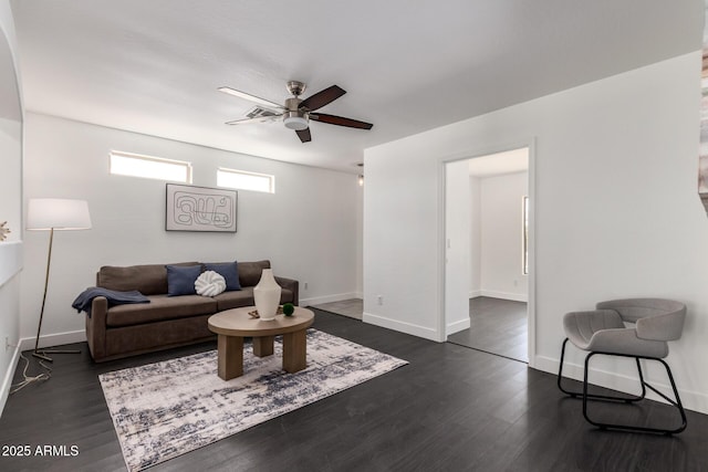 living area featuring dark wood-type flooring, baseboards, and a ceiling fan