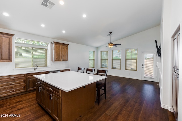 kitchen with a kitchen island, sink, vaulted ceiling, a breakfast bar area, and dark wood-type flooring