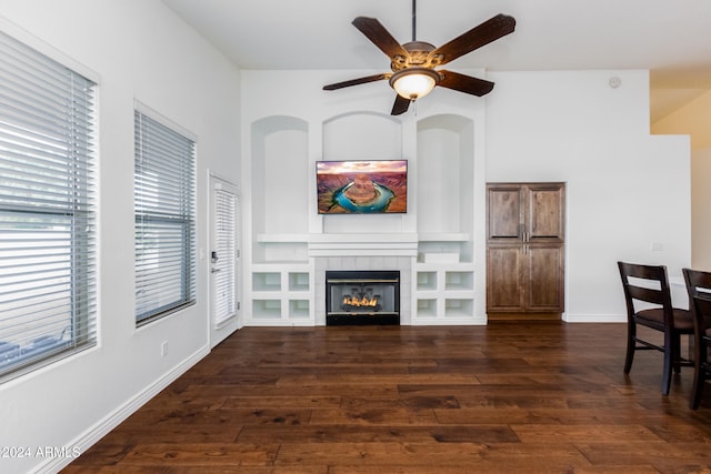 living room with dark wood-type flooring, a tiled fireplace, and ceiling fan