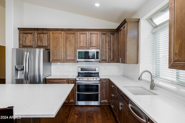 kitchen featuring lofted ceiling, dark wood-type flooring, sink, tasteful backsplash, and appliances with stainless steel finishes