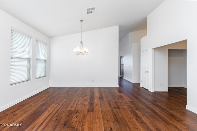 empty room featuring dark wood-type flooring, lofted ceiling, and a notable chandelier