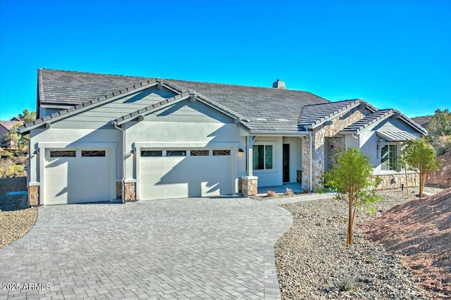 ranch-style house featuring a garage, stone siding, decorative driveway, a chimney, and a tile roof
