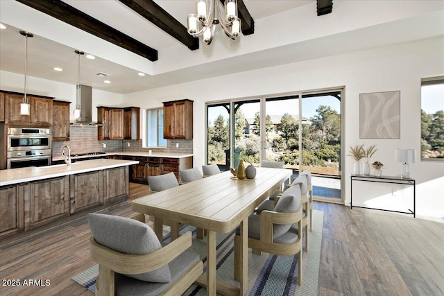 dining room featuring recessed lighting, beam ceiling, an inviting chandelier, and wood finished floors