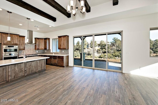 kitchen with wall chimney range hood, light countertops, wood finished floors, and double oven