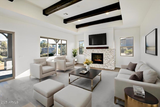 living area with a fireplace, beamed ceiling, wood finished floors, and visible vents