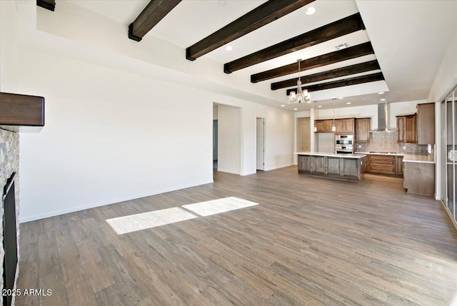 unfurnished living room with wood finished floors, beamed ceiling, baseboards, recessed lighting, and a notable chandelier
