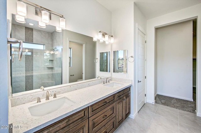 bathroom featuring baseboards, a shower stall, a sink, and tile patterned floors