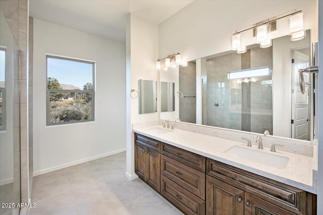 bathroom with baseboards, a sink, double vanity, and tiled shower