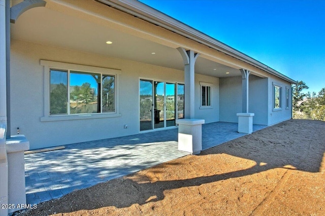 back of property featuring a patio area and stucco siding